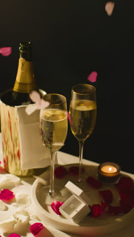 Vertical-Video-Of-Table-Set-For-Romantic-Marriage-Proposal-With-Confetti-Champagne-And-Engagement-Ring